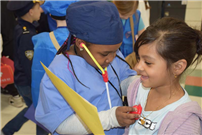 One student dressed as a doctor and using a fake stethoscope on another student thumbnail243431